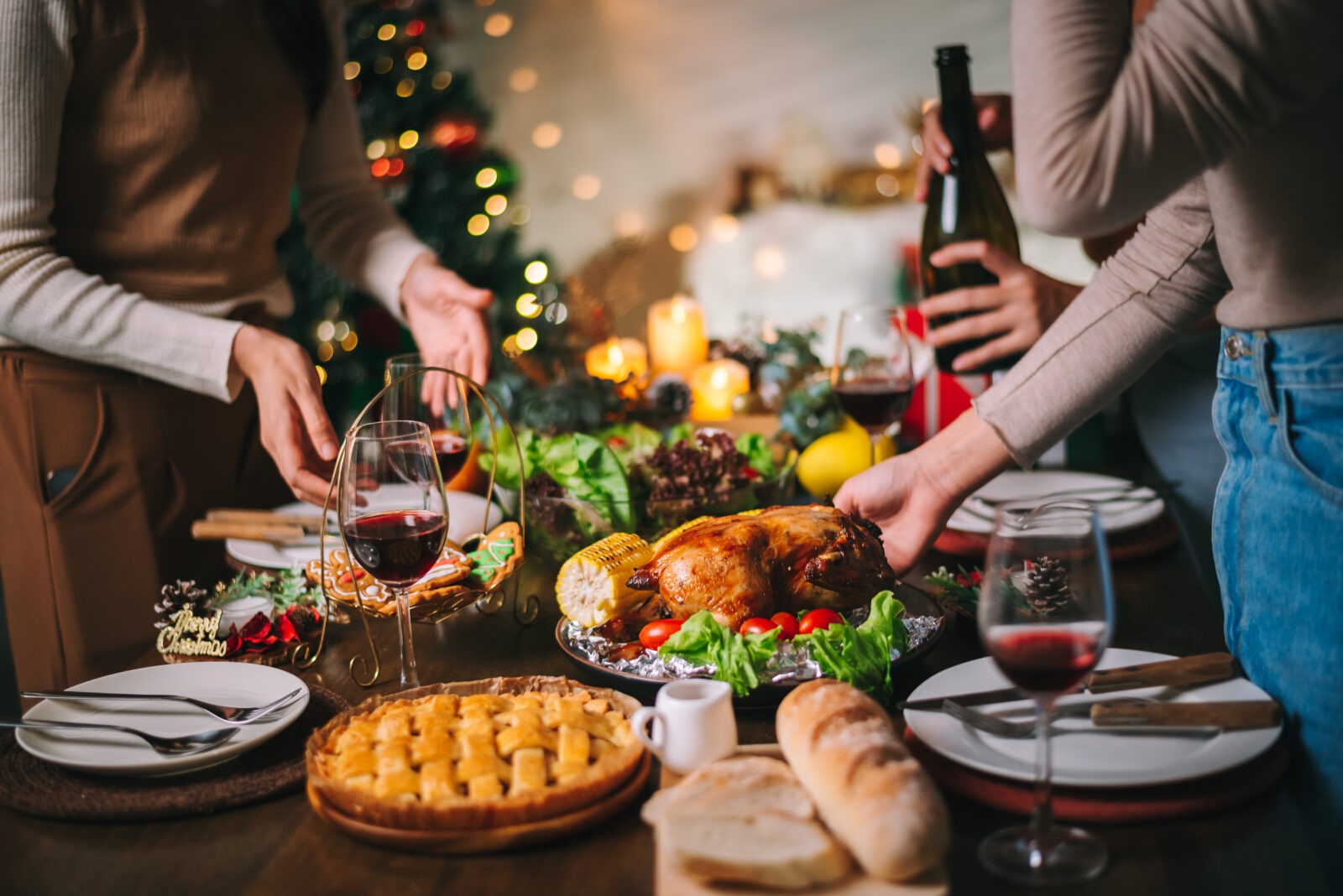 Close up Christmas or Thanksgiving dinner table infront of fireplace and xmas tree decorated at home